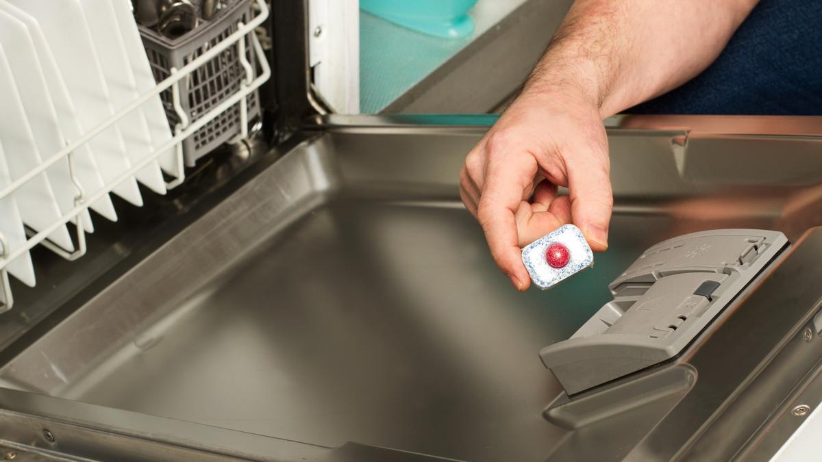 Un hombre coloca una pastilla en el cajetín del lavaplatos.