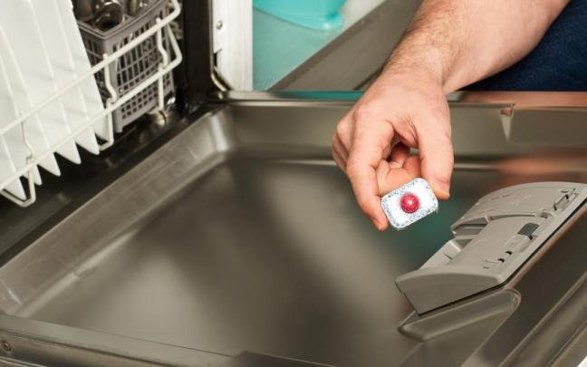 Un hombre coloca una pastilla en el cajetín del lavaplatos.