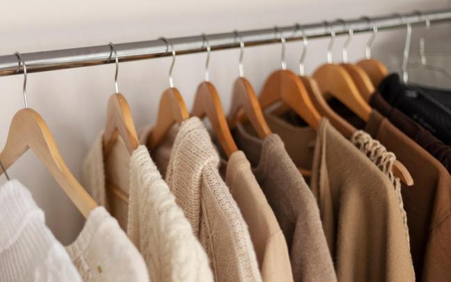 Jerseys y chaquetas cuelgan de la barra de un armario.