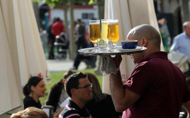 Un camarero sirve unas cervezas en la terraza de un bar.