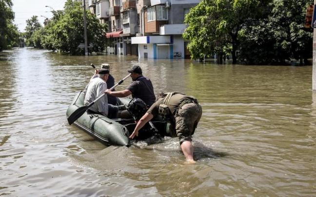 Un grupo de personas son trasladadas en una barca en una calle inundada de Jersón tras la destrucción de la presa.