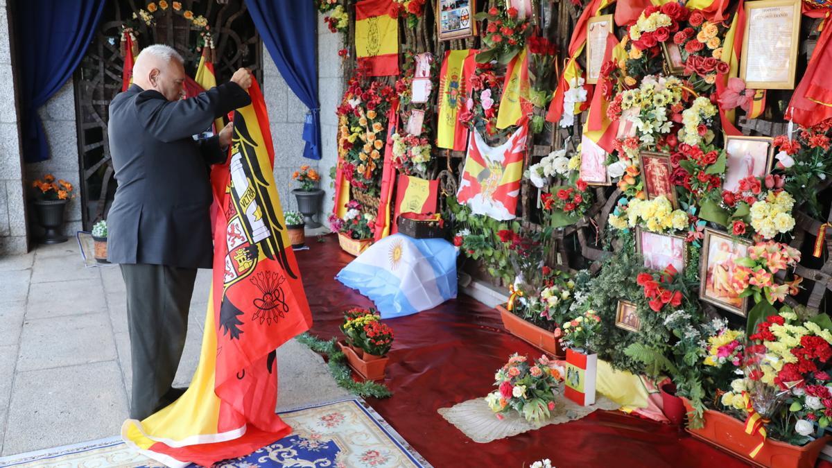 Un hombre despliega una bandera franquista durante un homenaje organizado por el Movimiento Católico Español frente a la tumba de Franco en el cementerio de Mingorrubio.