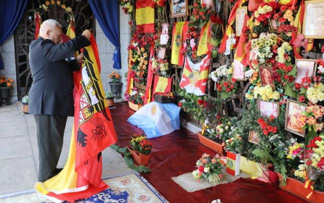 Un hombre despliega una bandera franquista durante un homenaje organizado por el Movimiento Católico Español frente a la tumba de Franco en el cementerio de Mingorrubio.