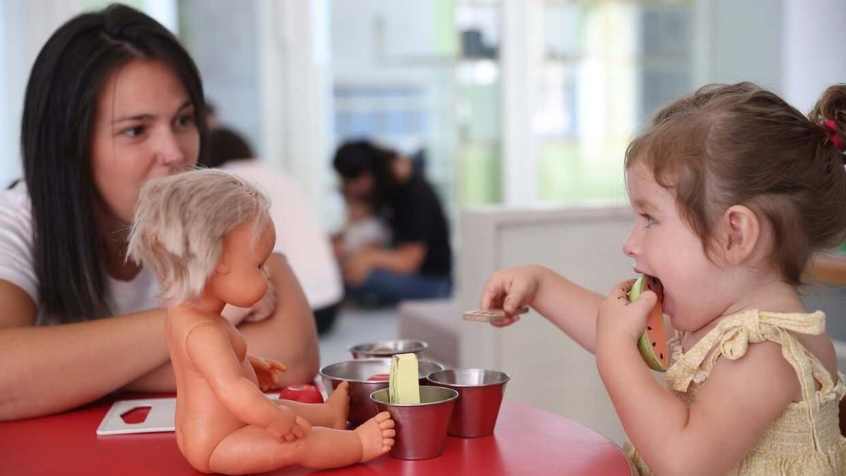 Una educadora juega con una niña en una escuela infantil.