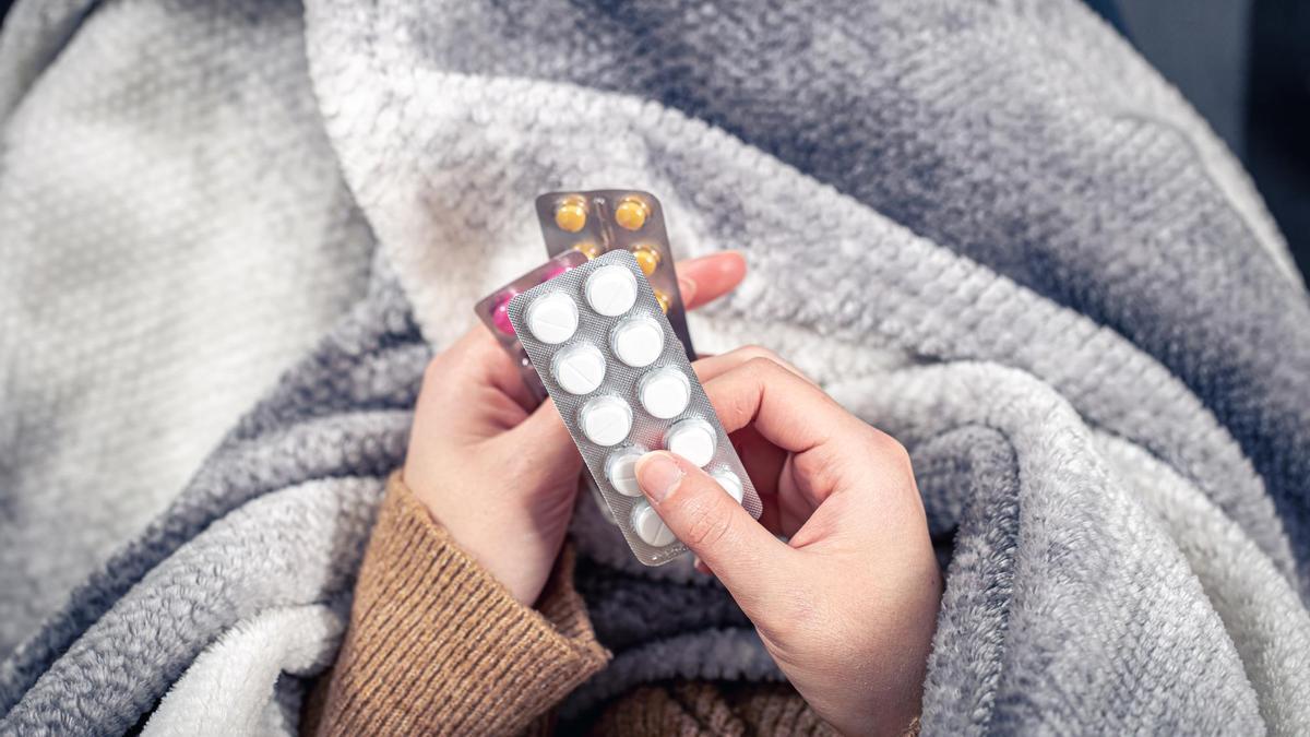 Una persona resfriada sostiene un medicamento.