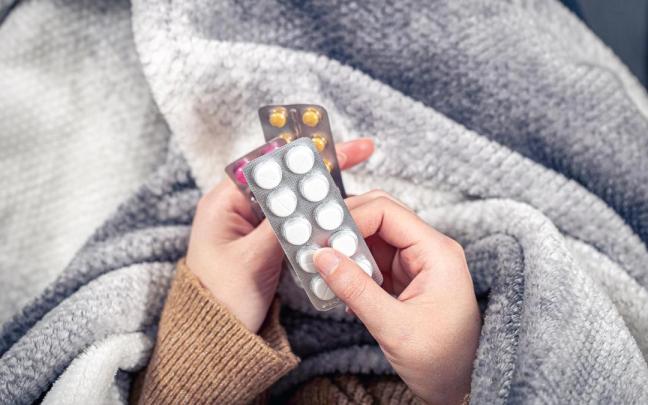 Una persona resfriada sostiene un medicamento.