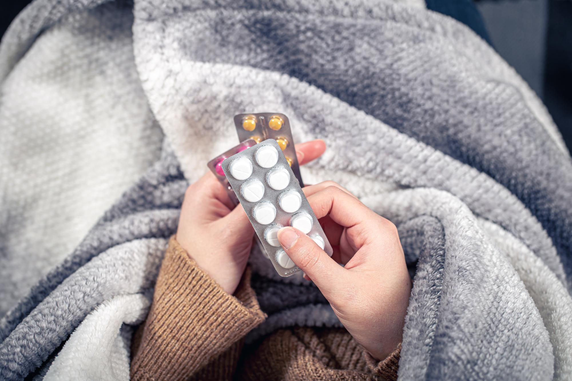 Una persona resfriada sostiene varios medicamentos.