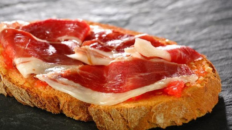 Una tostada de jamón con tomate.