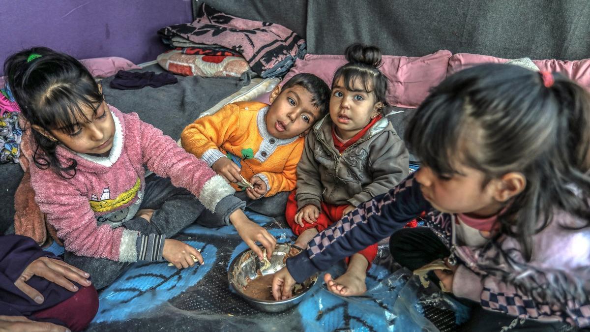Un grupo de niños intentan comer algo en un campo de refugiados en Rafah.