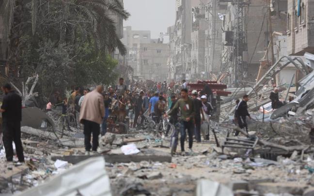 Ciudadanos palestinos caminan entre los escombros de edificios destruidos en Nuseirat.