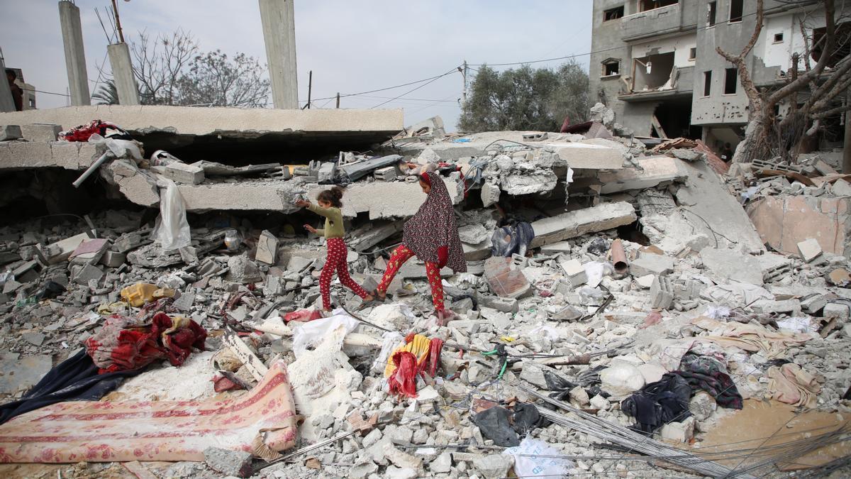 Dos niñas palestinas andan sobre los escombros de un edificio en Rafah.