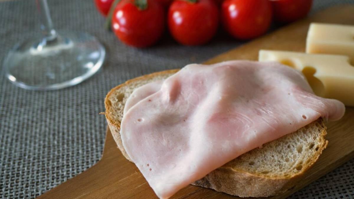 Jamón cocido sobre una rebanada de pan acompañado con un poco de queso.