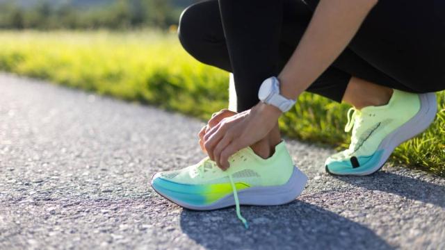 Primer plano de las manos de una mujer atándose los cordones de las zapatillas de correr