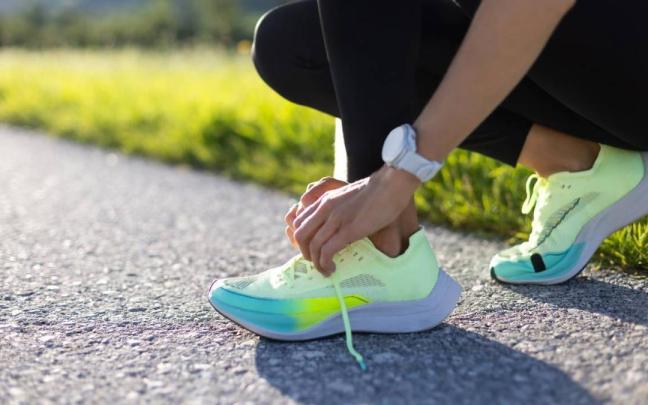 Primer plano de las manos de una mujer atándose los cordones de las zapatillas de correr