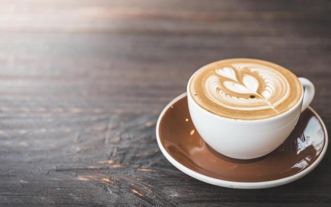 Una apetecible taza de café con leche con una flor dibujada en la espuma. Una apetecible taza de café con leche con una flor dibujada en la espuma.