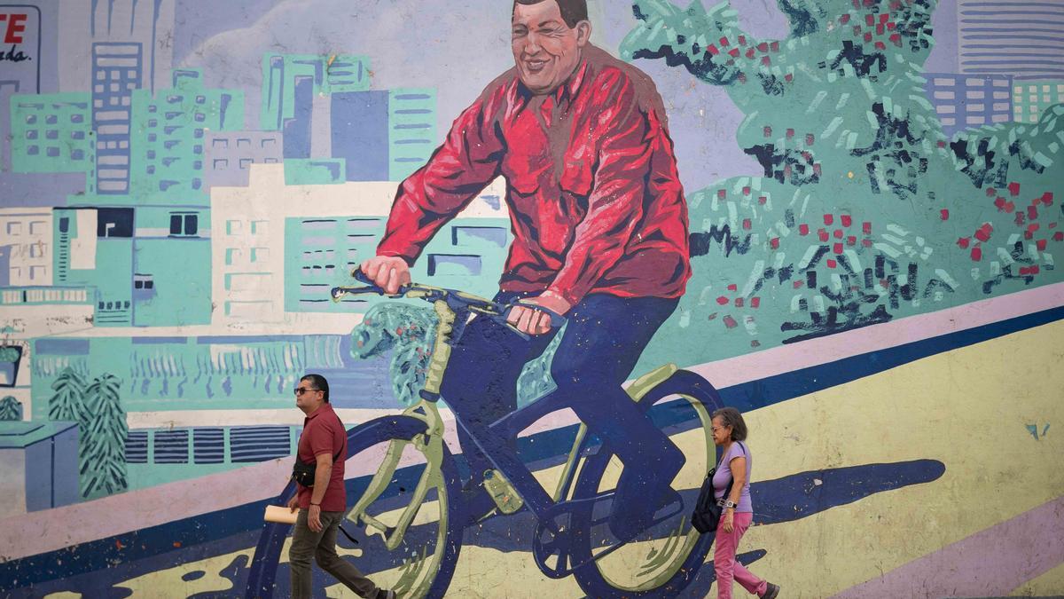 Venezolanos pasean frente a un mural en honor a Chávez.