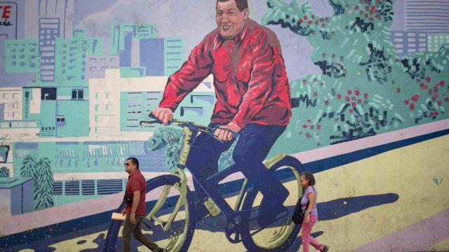 Venezolanos pasean frente a un mural en honor a Chávez.