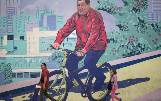 Venezolanos pasean frente a un mural en honor a Chávez.