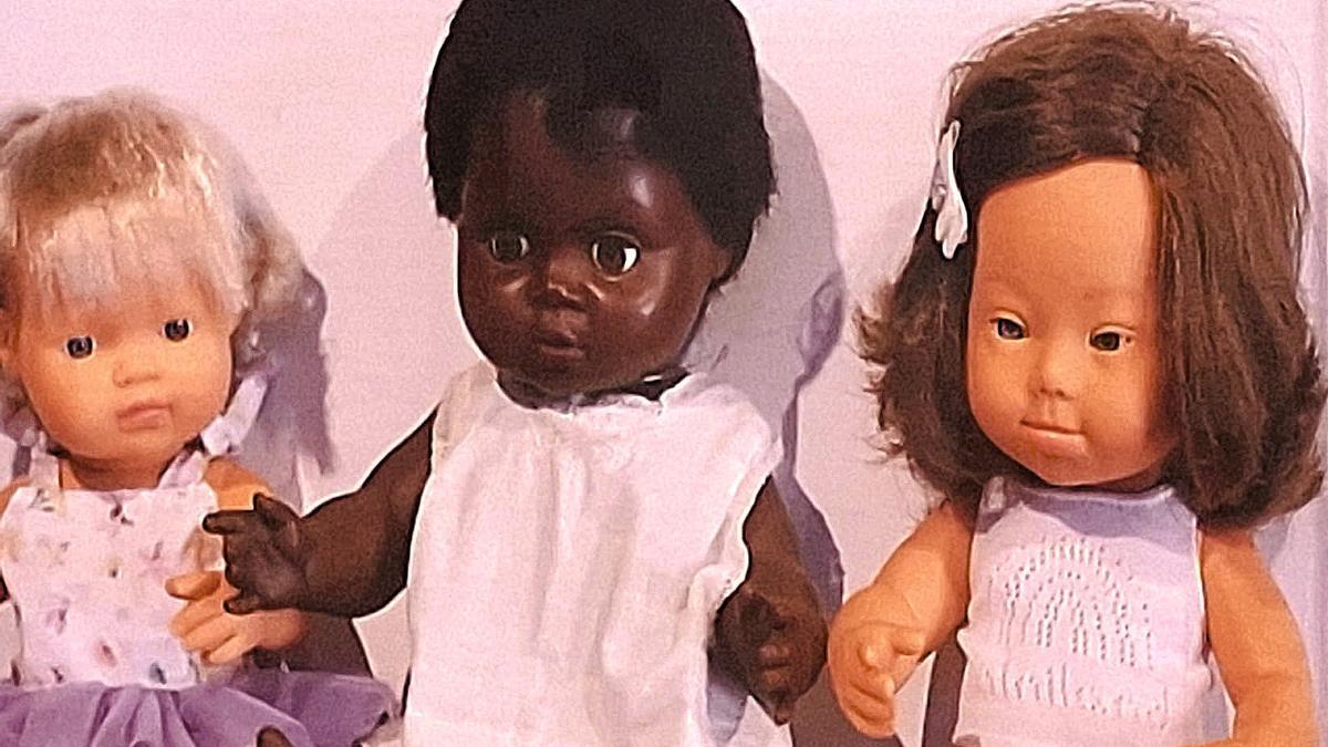 Muñecas de raza blanca y negra, junto a otra con Síndrome de Down