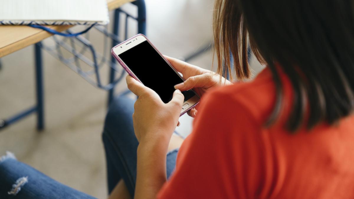 Una niña con un móvil en clase.