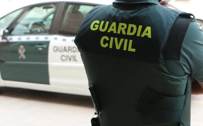 Un agente de la Guardia Civil, de espaldas, junto a un vehículo oficial