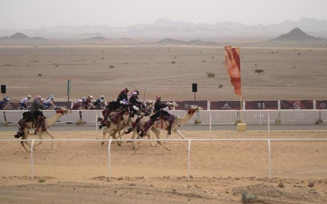 Los ciclistas ruedan en paralelo al circuito de las carreras de dromedarios.