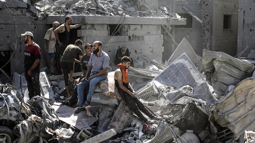Ciudadanos palestinos entre los escombros de un edificio atacado en Gaza
