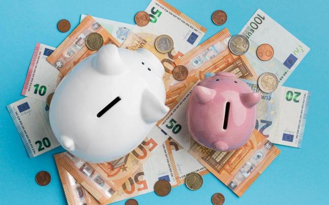 Billetes y monedas de euro junto a dos huchas.