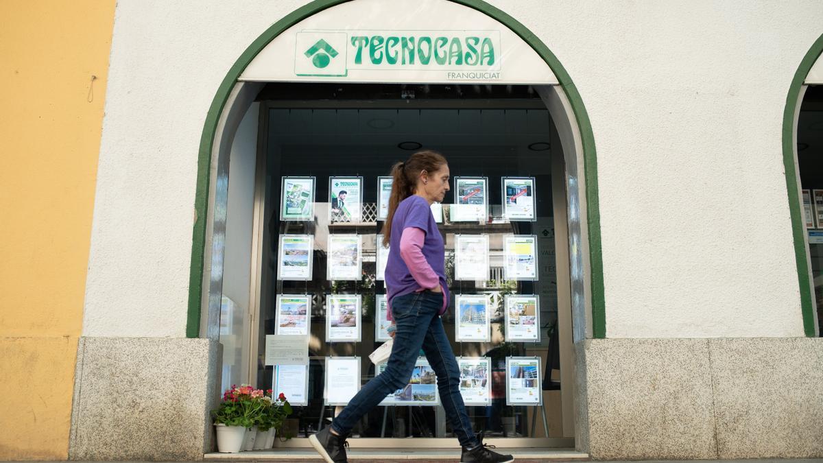 Una mujer pasa frente a una agencia inmobiliaria.
