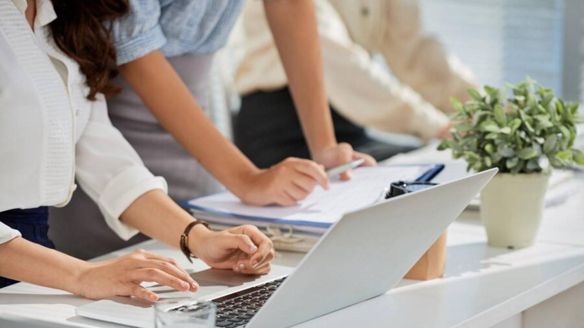 Personas reunidas en su puesto de trabajo con el ordenador