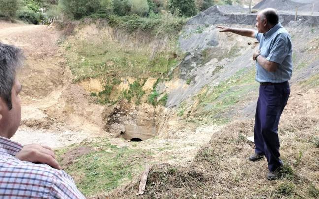 Unas personas señalan la zona donde se produjo el hundimiento de tierras.