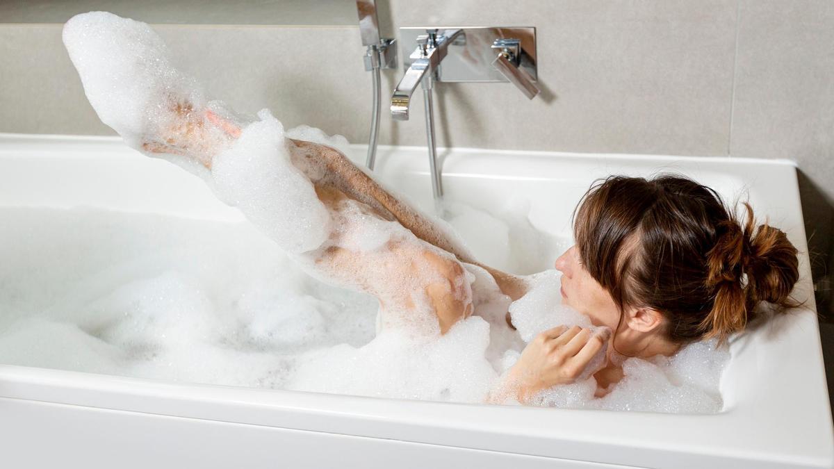 Una mujer disfruta de un baño de espuma en su casa.