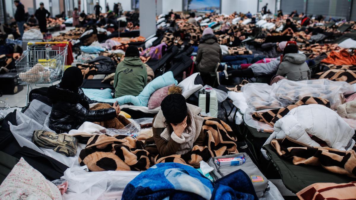 Varias personas descansan en un centro comercial destinado a la acogida temporal de los refugiados que vienen a Polonia.