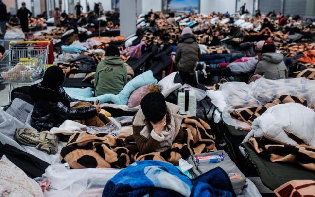 Varias personas descansan en un centro comercial destinado a la acogida temporal de los refugiados que vienen a Polonia.