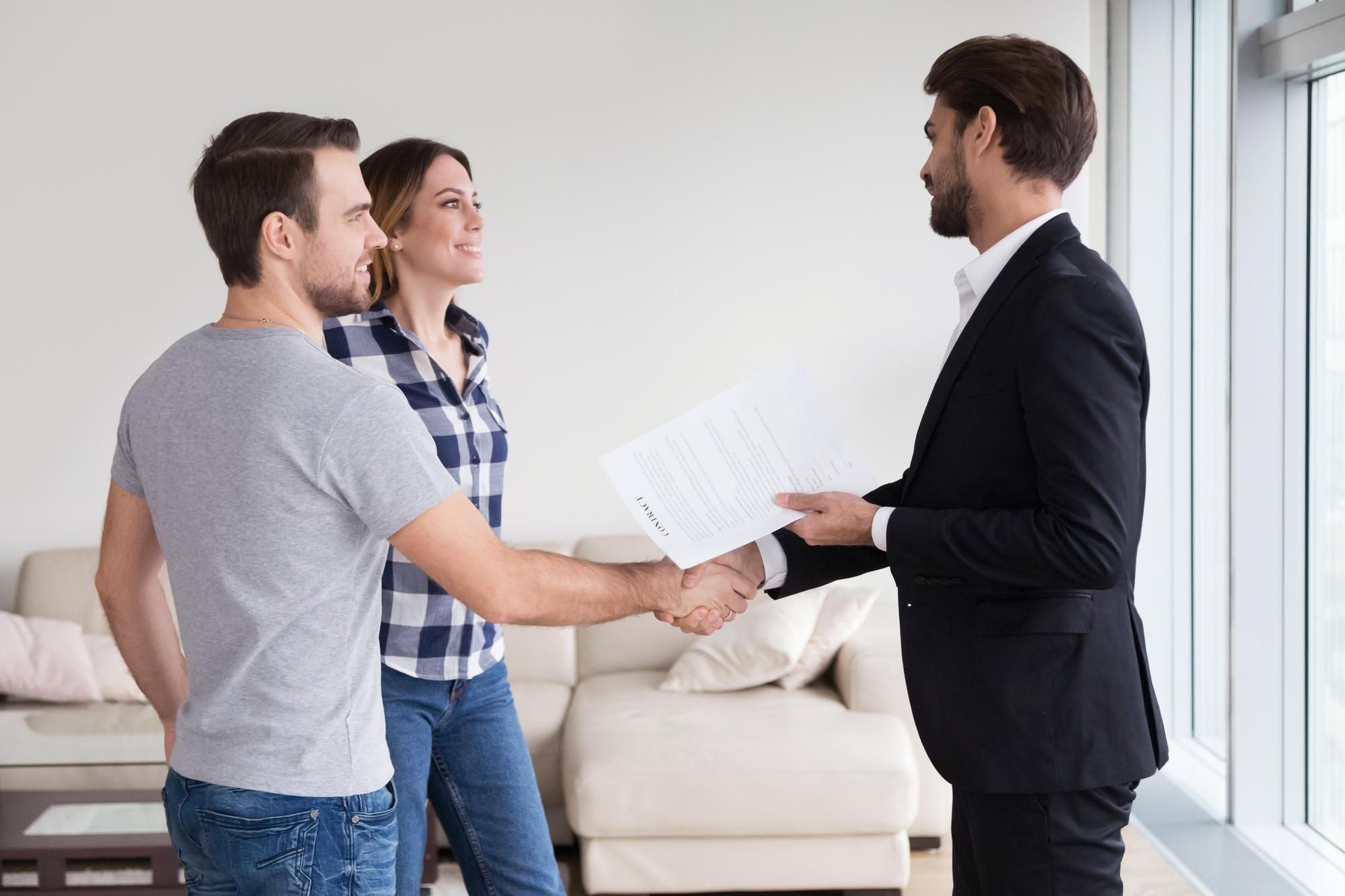 Un agente inmobiliario estrecha la mano a los compradores de una vivienda.