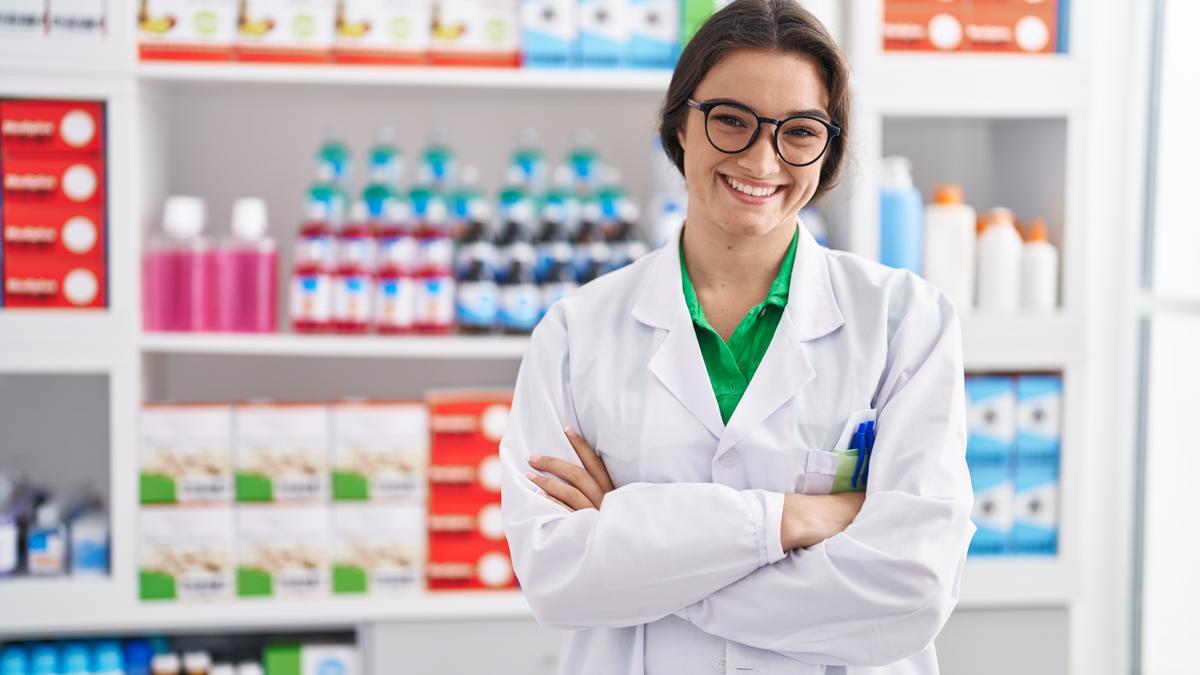 Una farmacéutica delante de una estantería con diferentes productos.