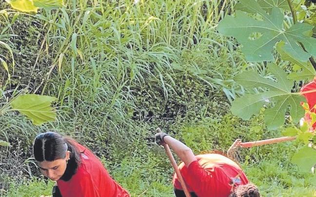 Dos jóvenes desbrozando el terreno de un camino rural en un Auzolandegi del Gobierno vasco. | FOTO: IREKIA