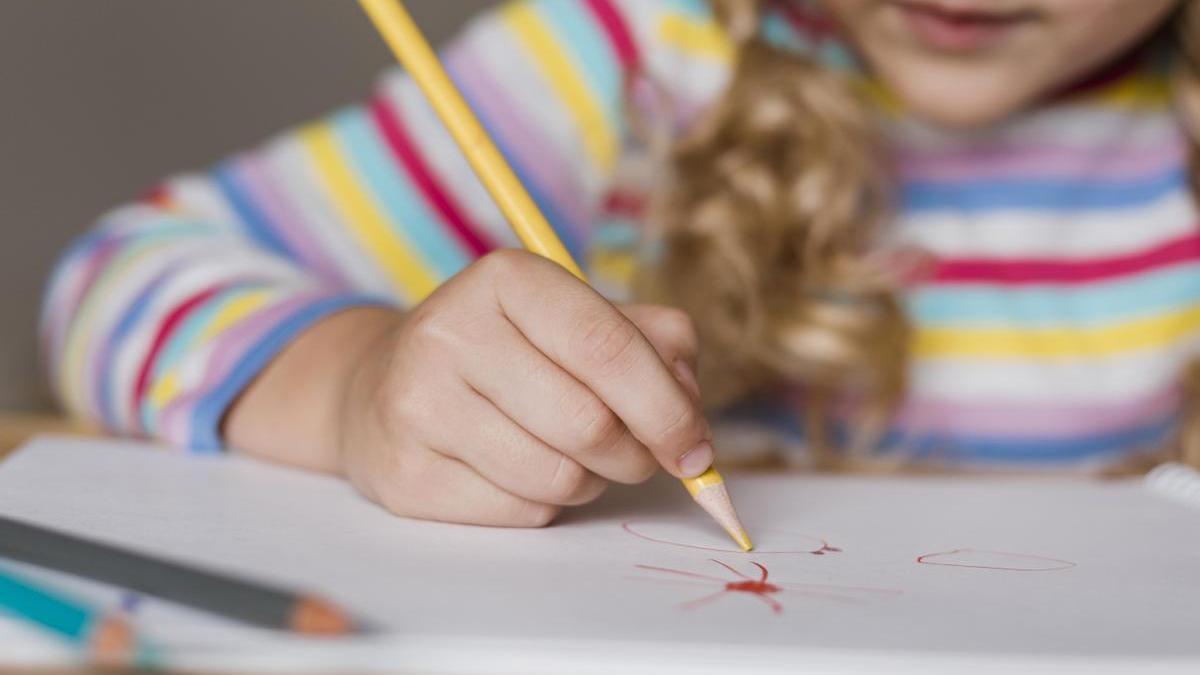 Niña hace un dibujo con pinturas de diferentes colores.
