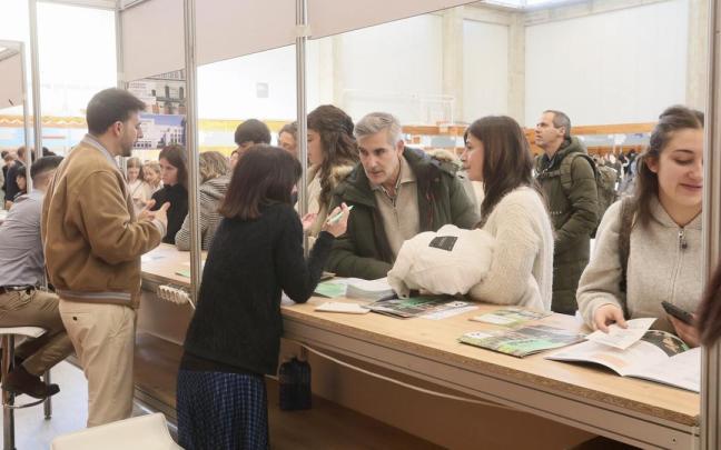 Jóvenes acuden junto a sus padres en una feria de orientación universitaria.