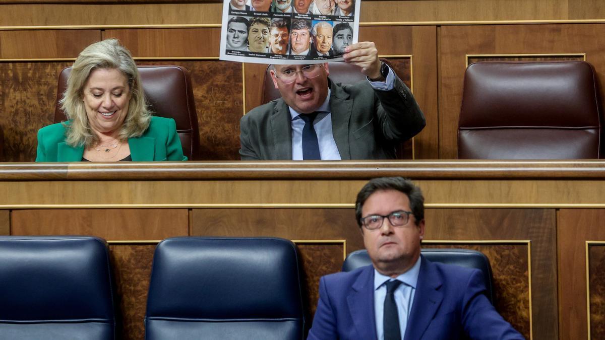 El portavoz del PP, Miguel Tellado, exhibe desde su escaño un cartel con la imagen de doce miembros del PSOE asesinados por ETA