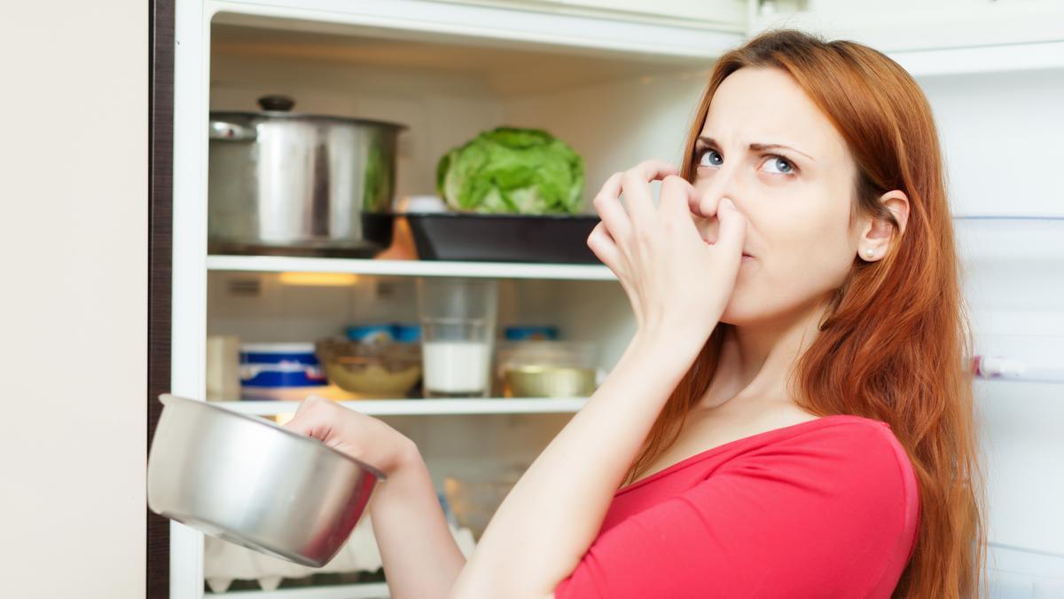 Mujer saca de la nevera alimentos en mal estado