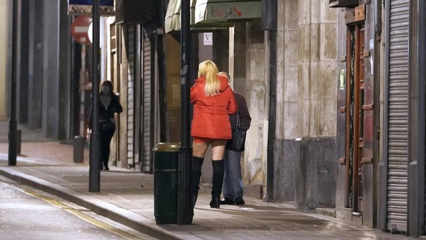 Una mujer que ejerce la prostitución conversa con un hombre en el barrio de las Cortes de Bilbao.