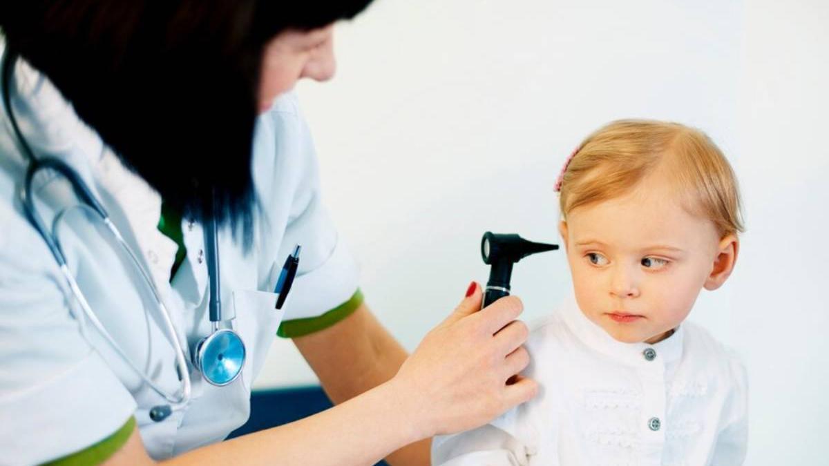 Pediatra examina el oído a una niña pequeña en la consulta