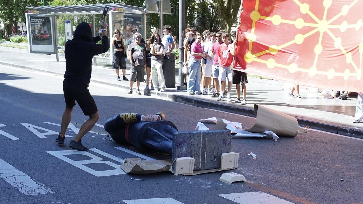 Varios manifestantes encapuchados derriban una estatua de Felipe VI durante la manifestación de la organización juvenil Ernai.