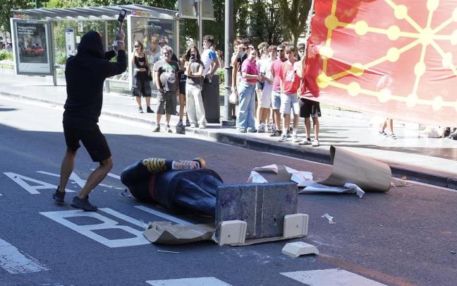 Varios manifestantes encapuchados derriban una estatua de Felipe VI durante la manifestación de la organización juvenil Ernai.