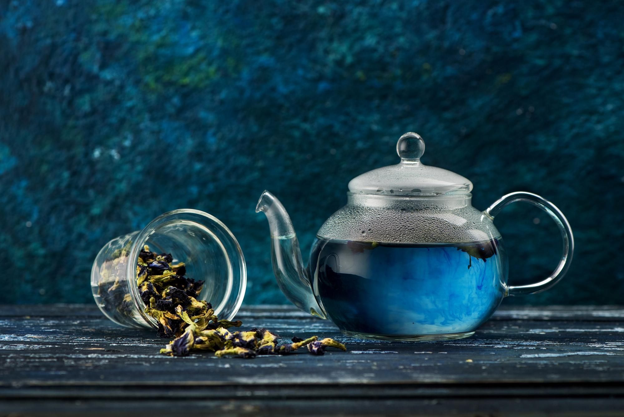 Té azul junto a varias hojas secas de flor de guisante de mariposa.