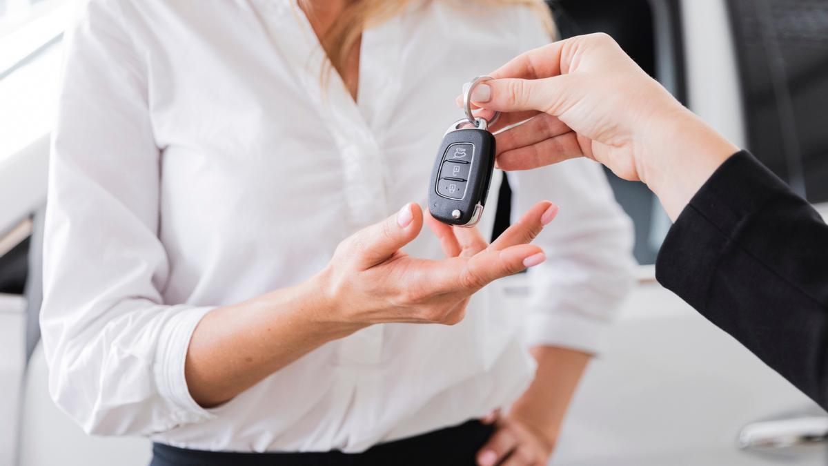 Una mujer recibe la llave de un coche.