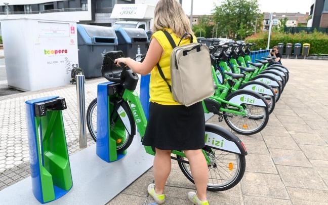 Una mujer coge una bicicleta en la estación de la plaza Harrobieta de Altza.