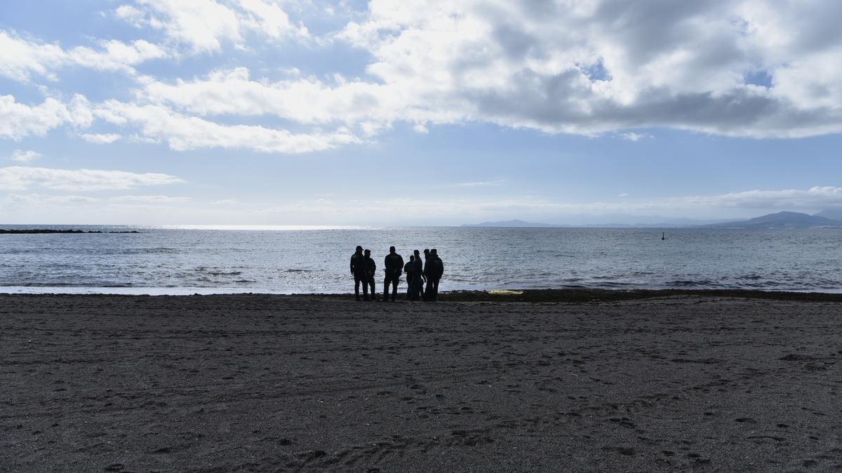 Guardias civiles frente a un cadáver de un migrante en la orilla de la playa de la Ribera