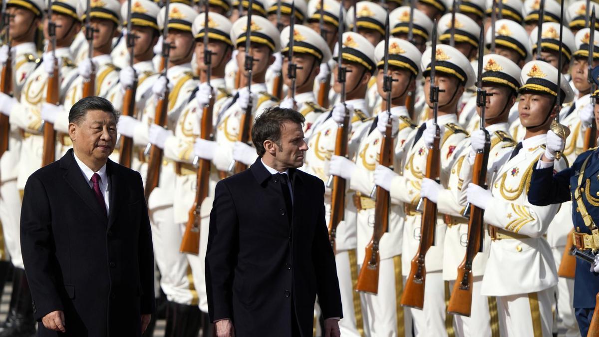 El presidente francés, Emmanuel Macron (d), inspecciona una guardia de honor con el presidente chino, Xi Jinping
